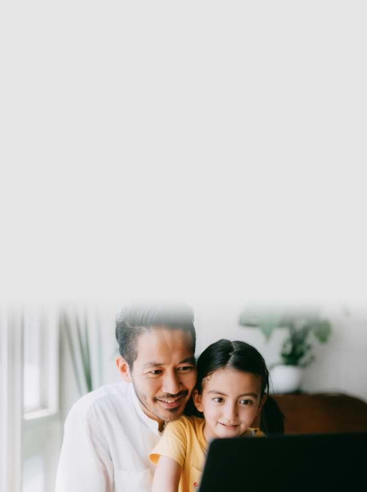 Dad and daughter looking at a laptop smiling.